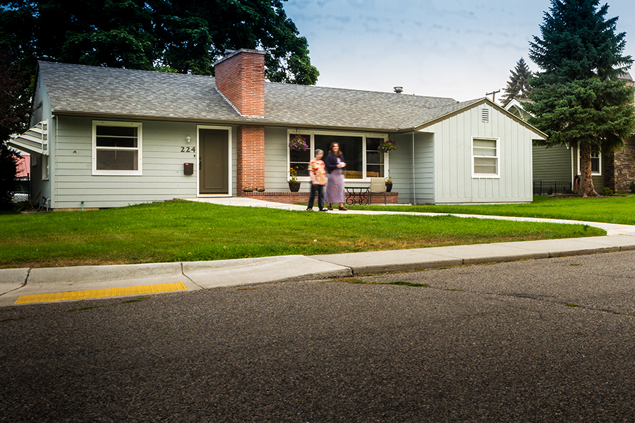 Two women slow to chat as they walk away from a one-story Visitable home.